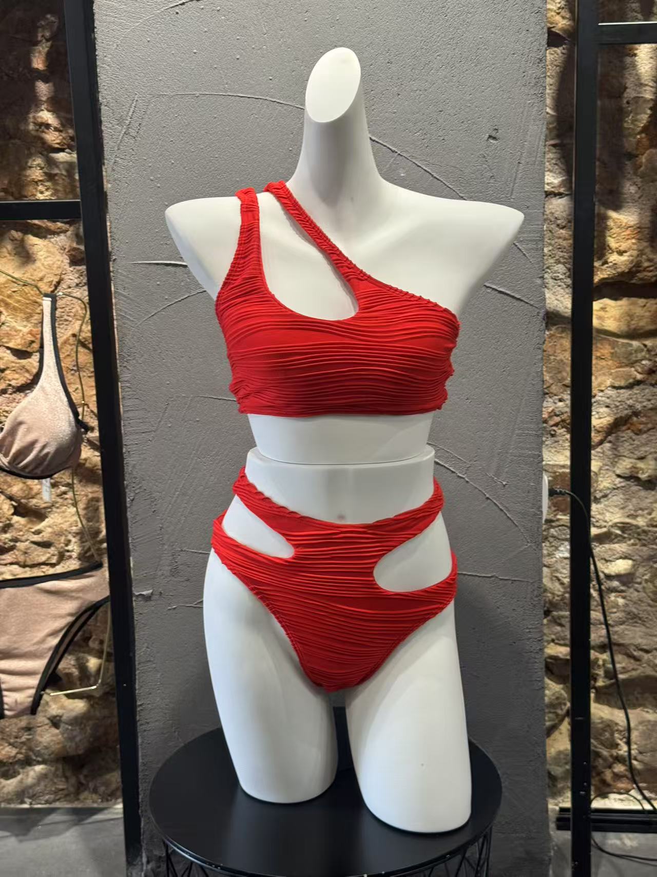 Red bikini set on a mannequin against a stone wall background