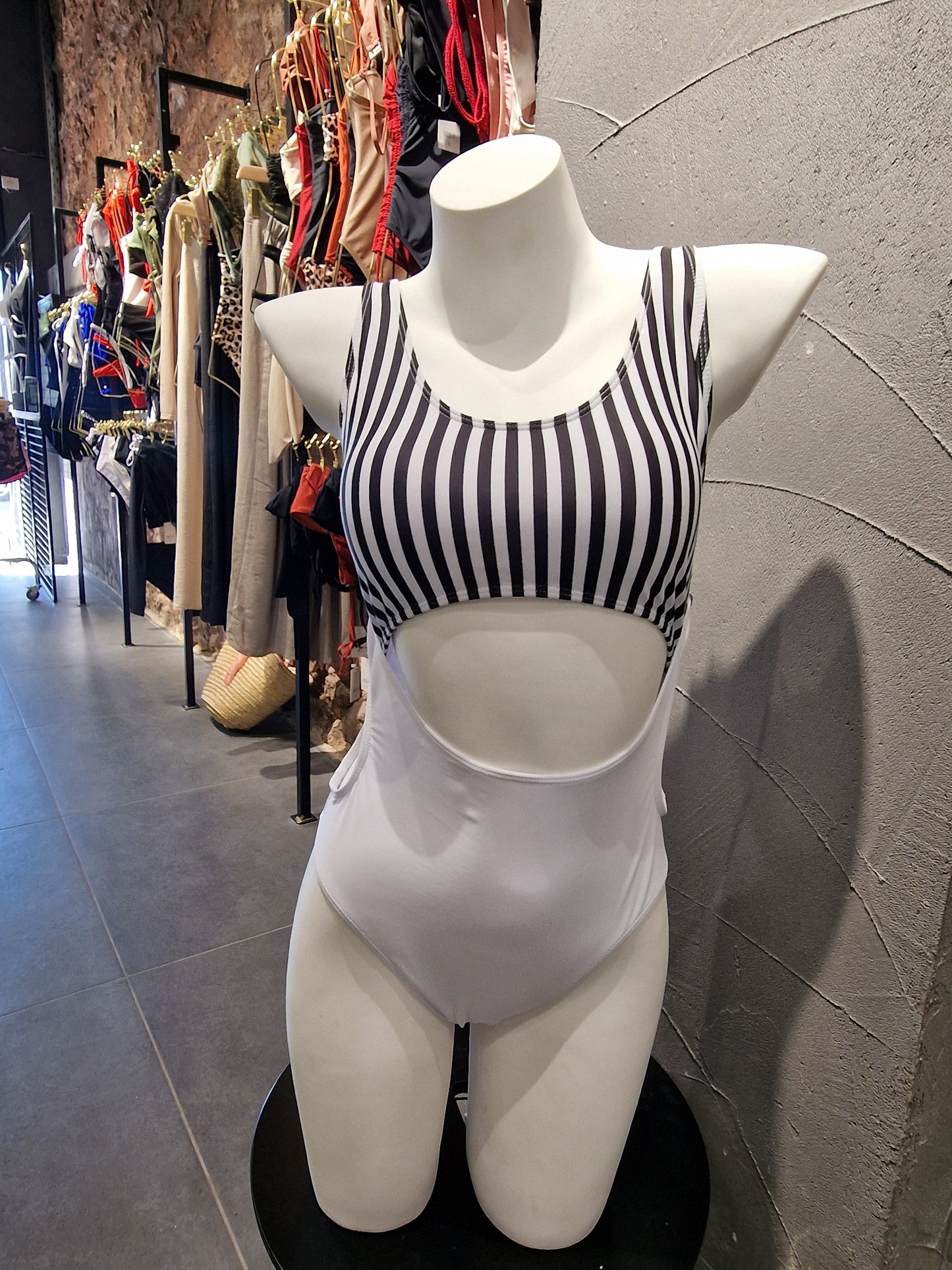 Mannequin wearing a black and white striped dress on a tiled floor.