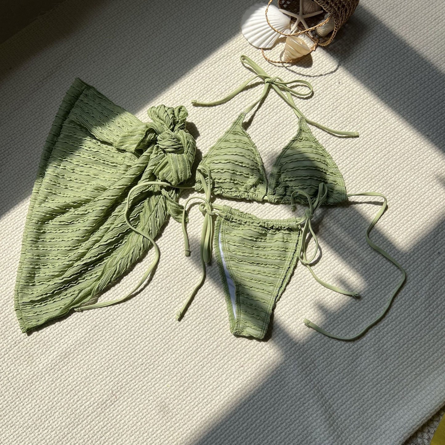 Green bikini set on a textured surface with sunlight casting shadows