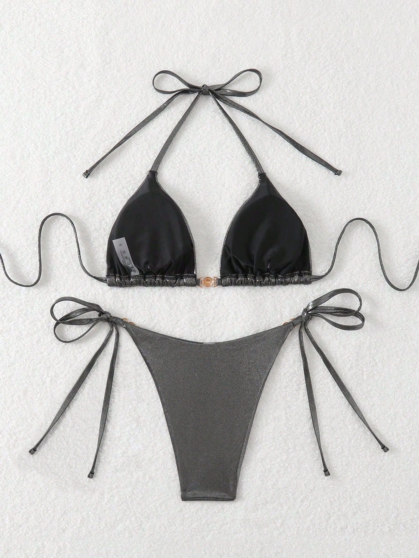 Black bikini set with bow details on a textured white background