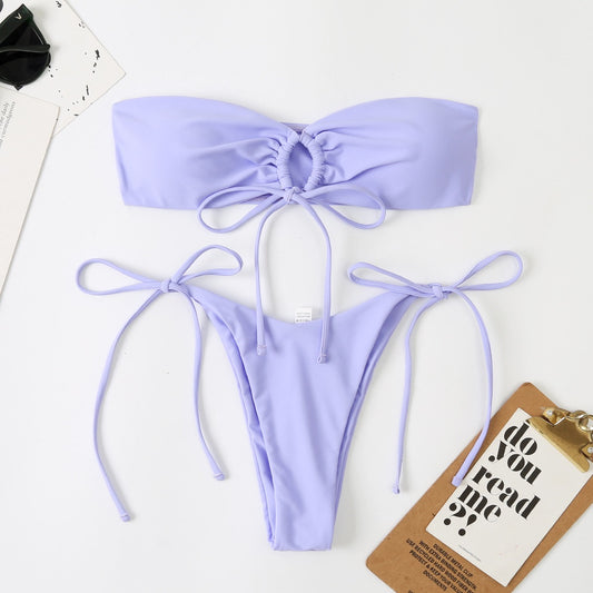 Lavender bikini set on a white background with a small brown box and black item.