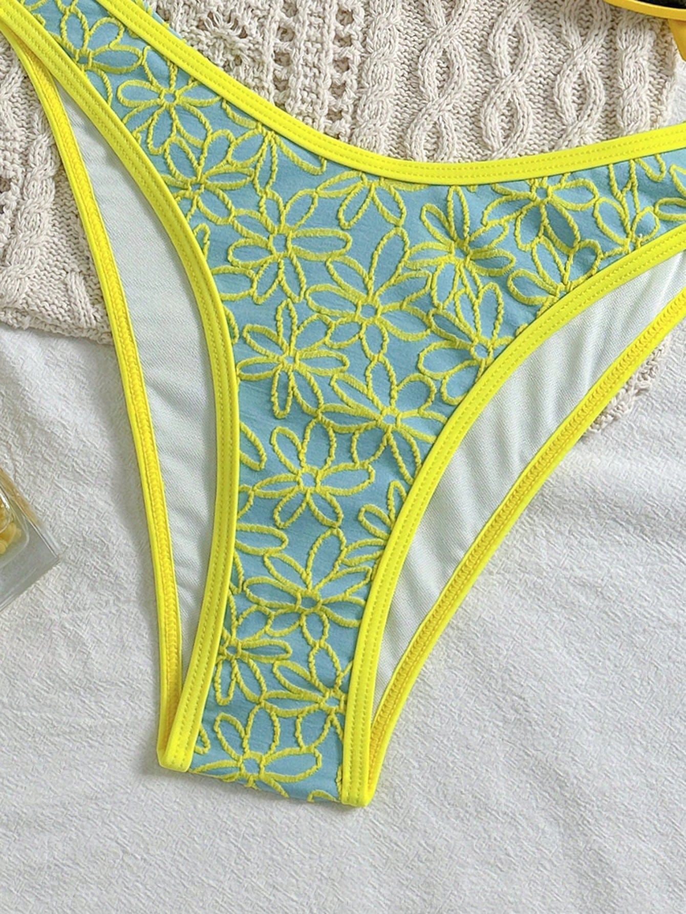 Lace-trimmed underwear with yellow floral patterns on a textured surface