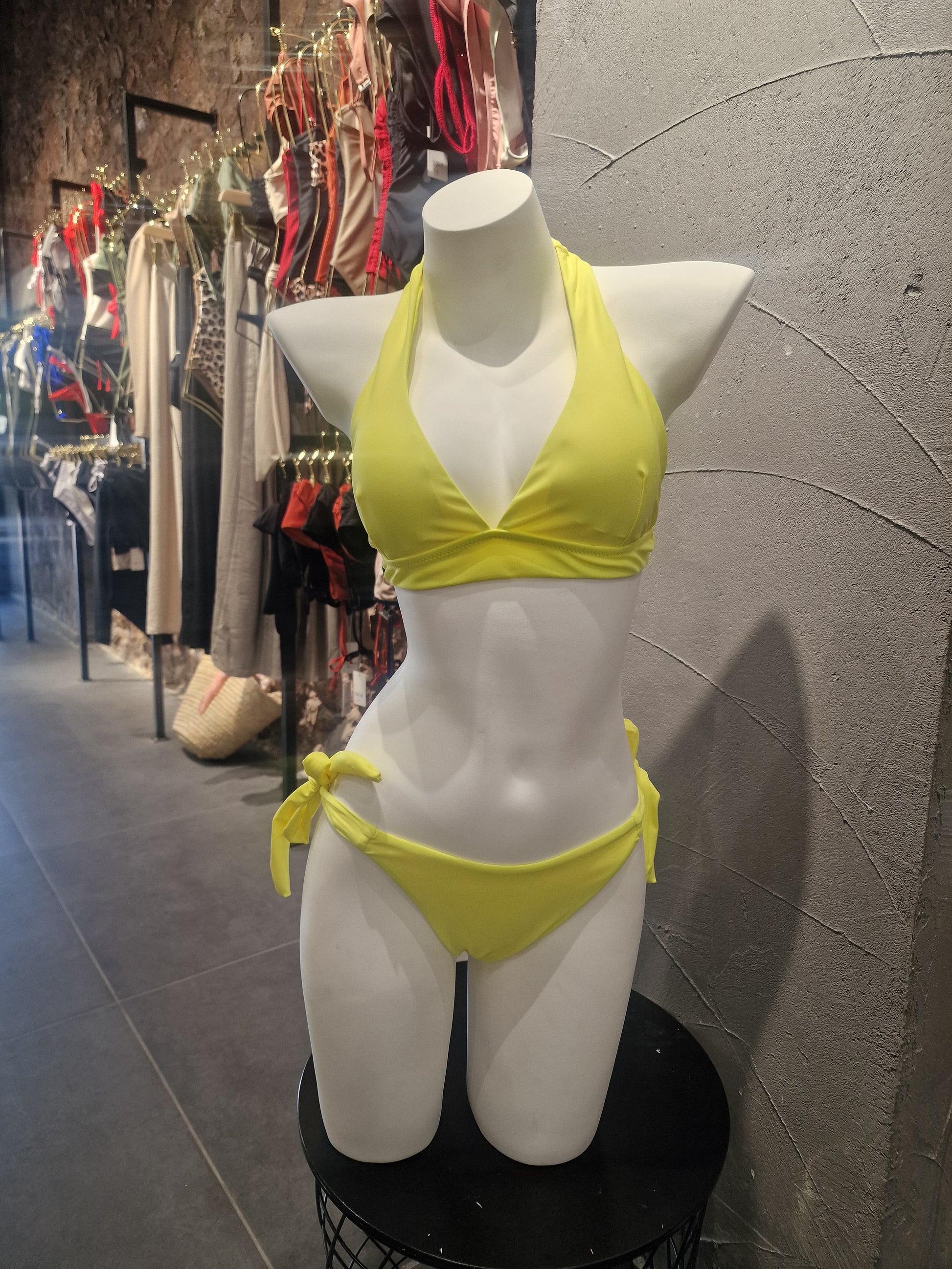 Mannequin wearing a yellow bikini on a tiled floor