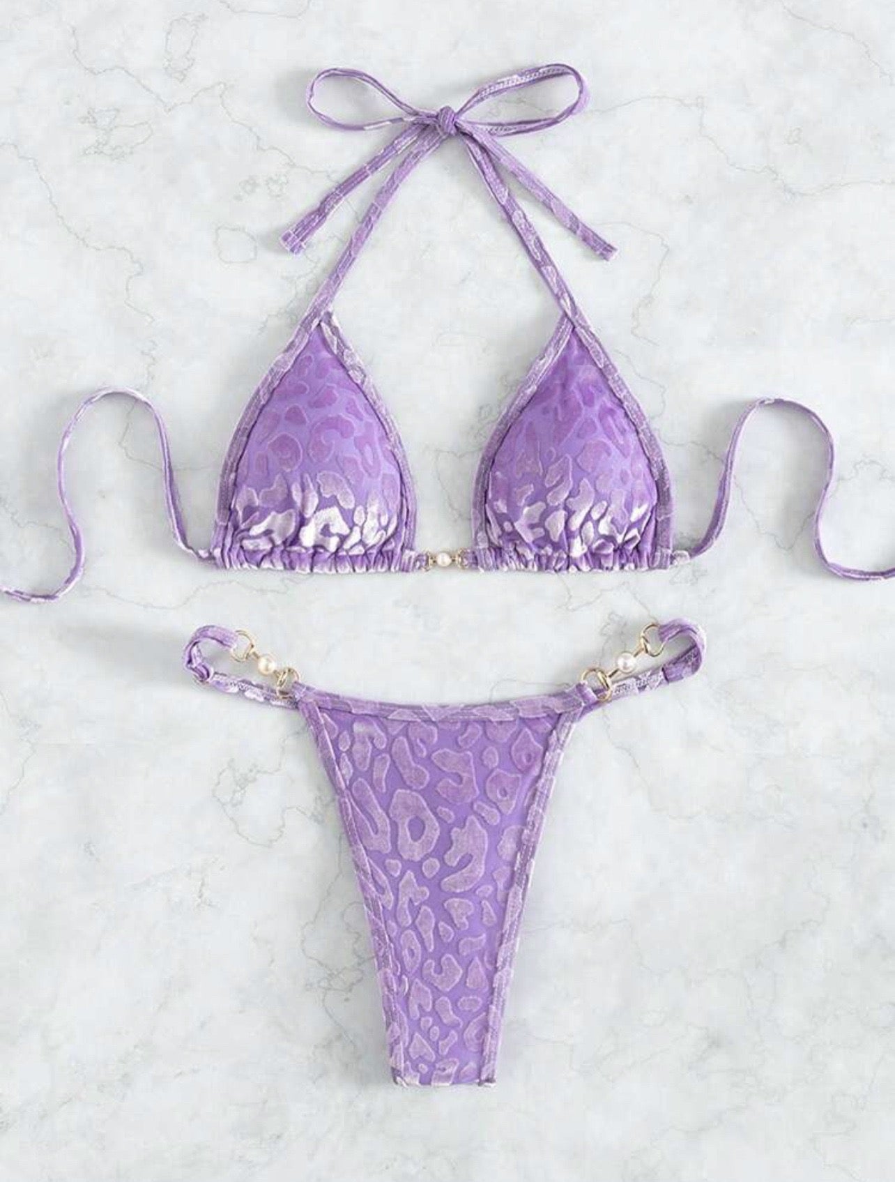 Purple bikini set with animal pattern on a light gray background