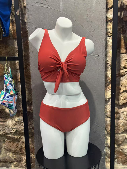 Red bikini set on a mannequin against a stone wall background