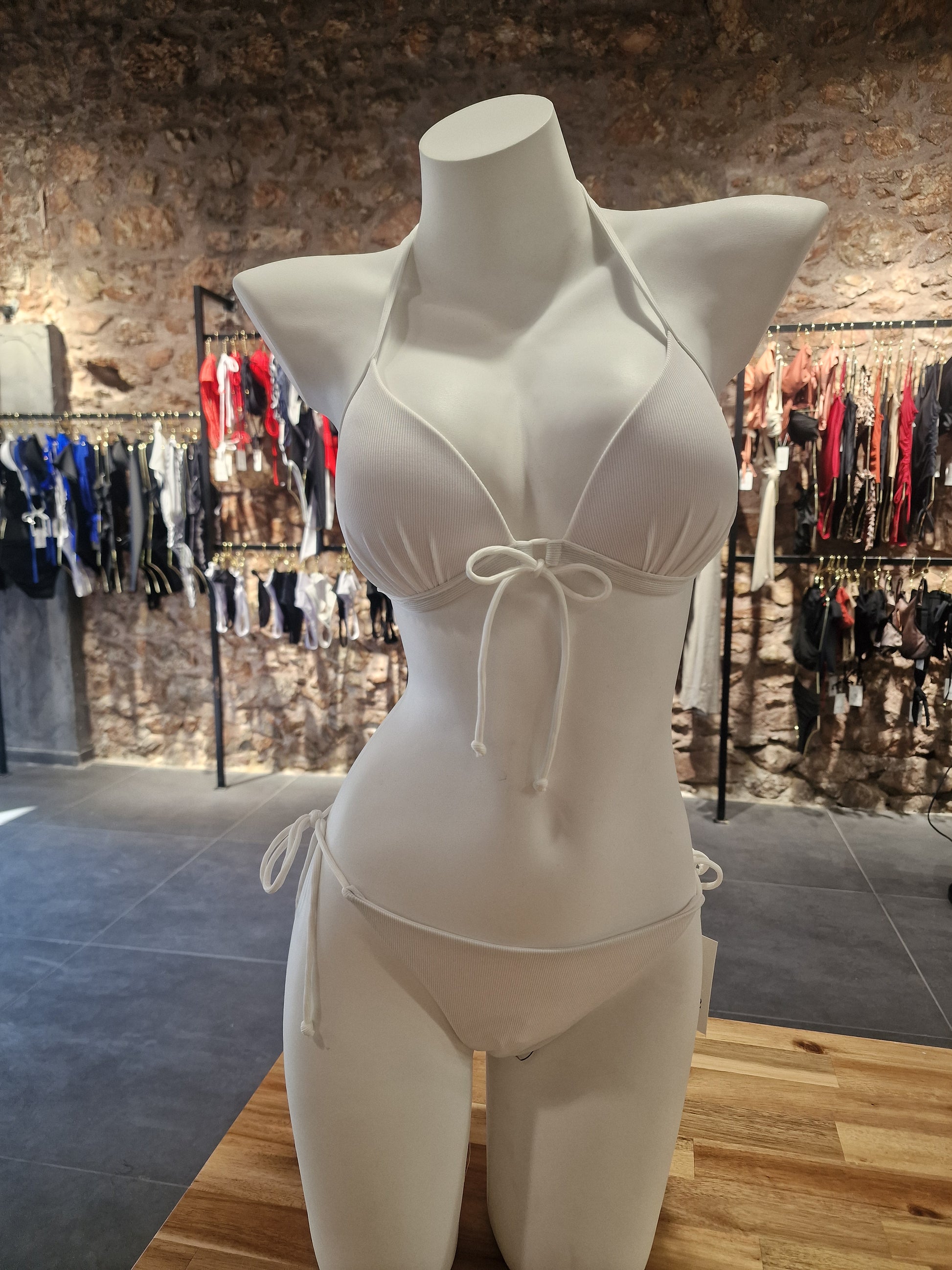 White bikini on a mannequin with a blurred store background