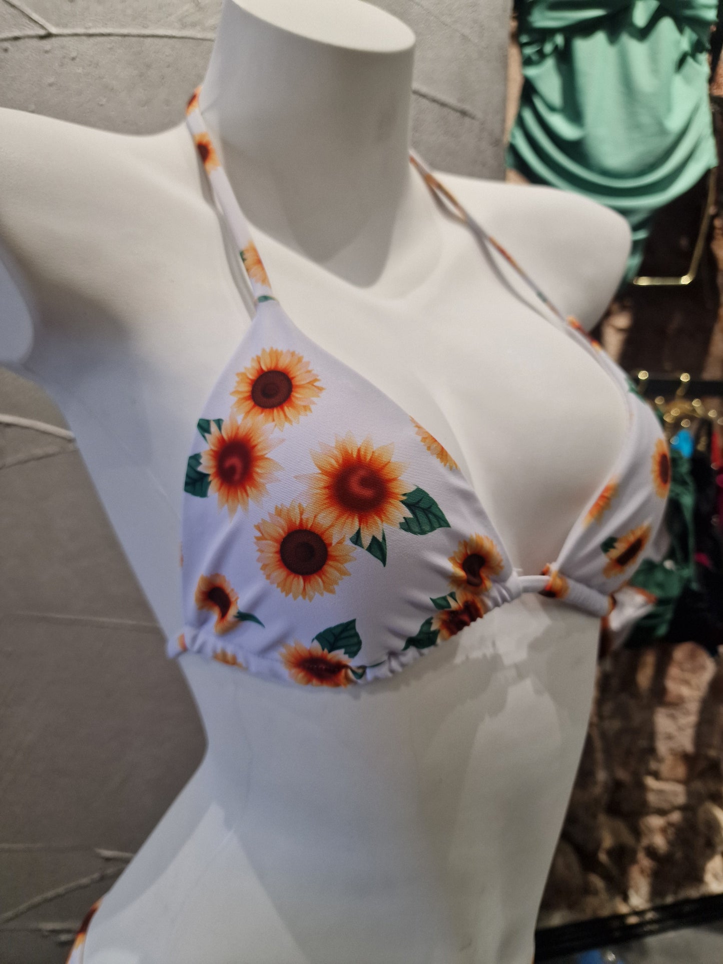 White bikini with sunflower pattern on a mannequin against a blurred background