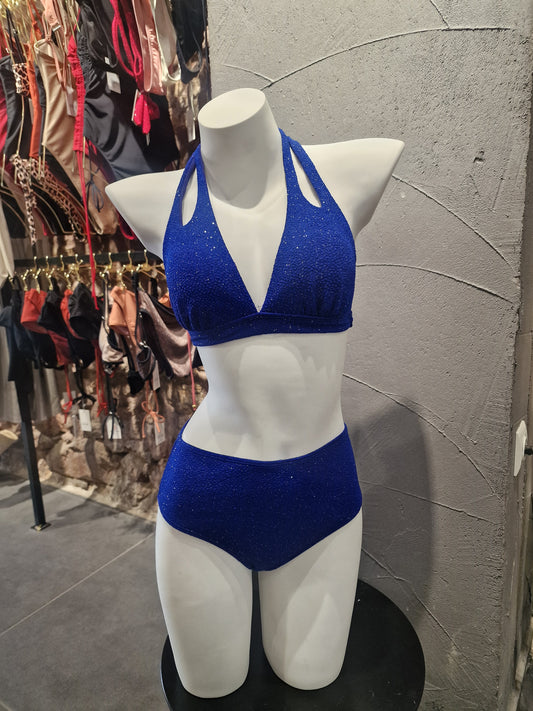 White glove with blue bandage on a mannequin hand against a textured wall.

