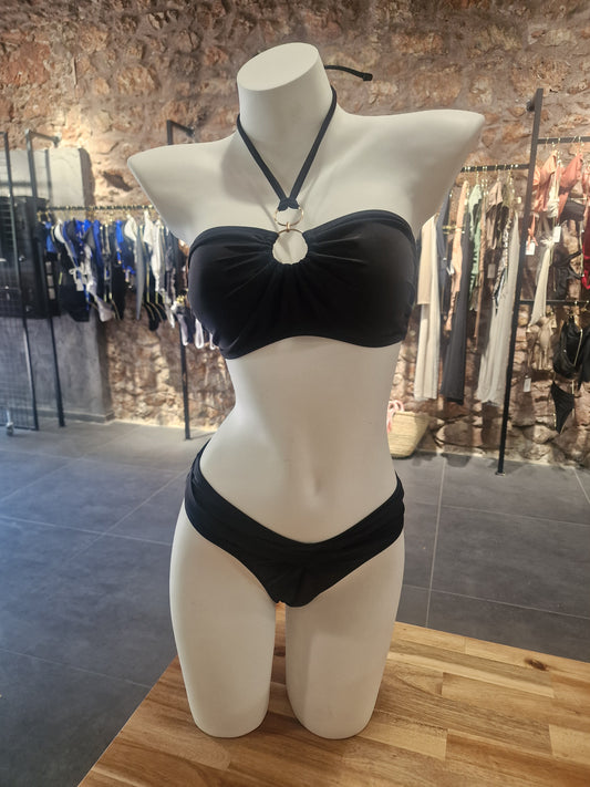  Mannequin wearing a black dress with a bow on a wooden floor.

