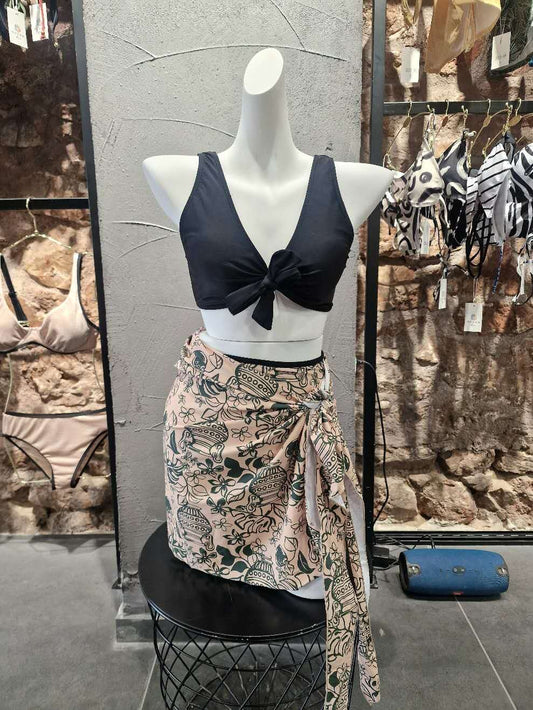 Mannequin wearing a black top and patterned skirt with a store interior background.

