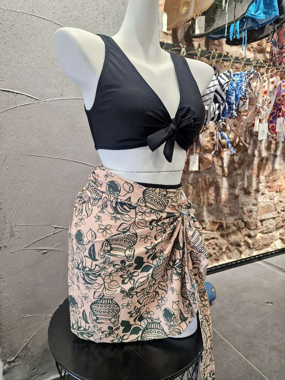 Mannequin wearing a black top and patterned skirt with a blurred background