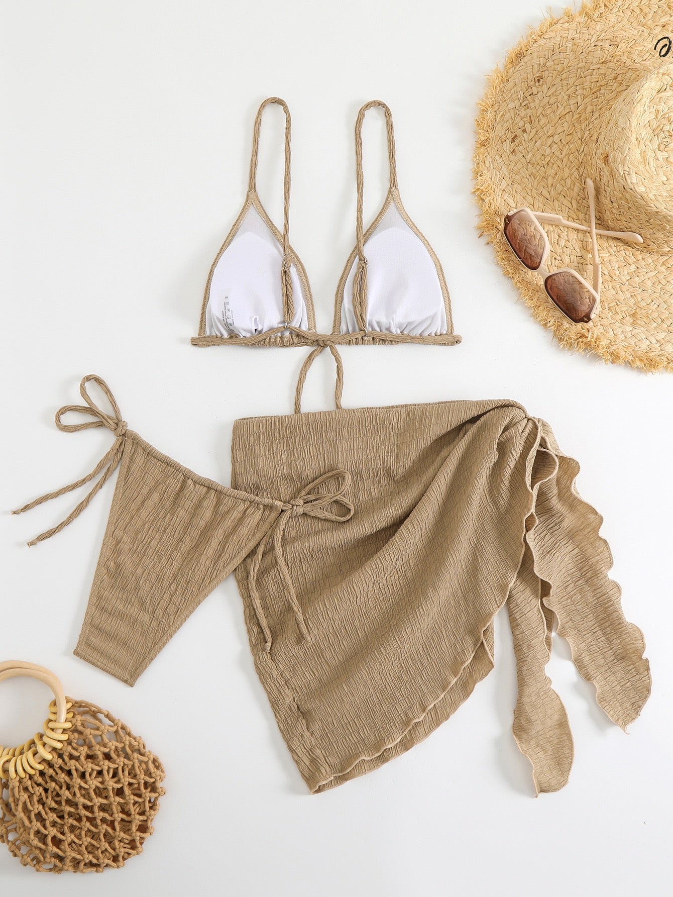 Beige bikini set with matching cover-up and straw hat on a white background

