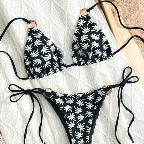Black bikini set with white floral patterns on a textured surface

