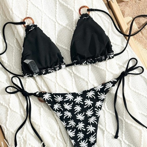 Black bikini with white palm tree pattern on a textured surface

