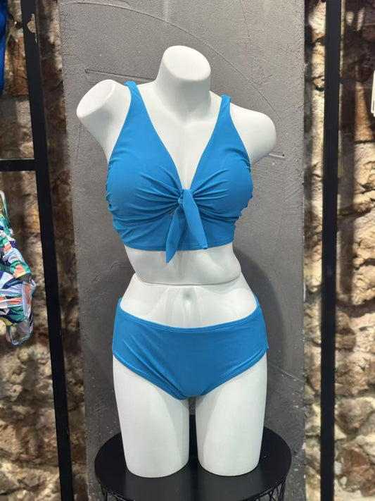 Blue bikini set on a mannequin against a stone wall background
