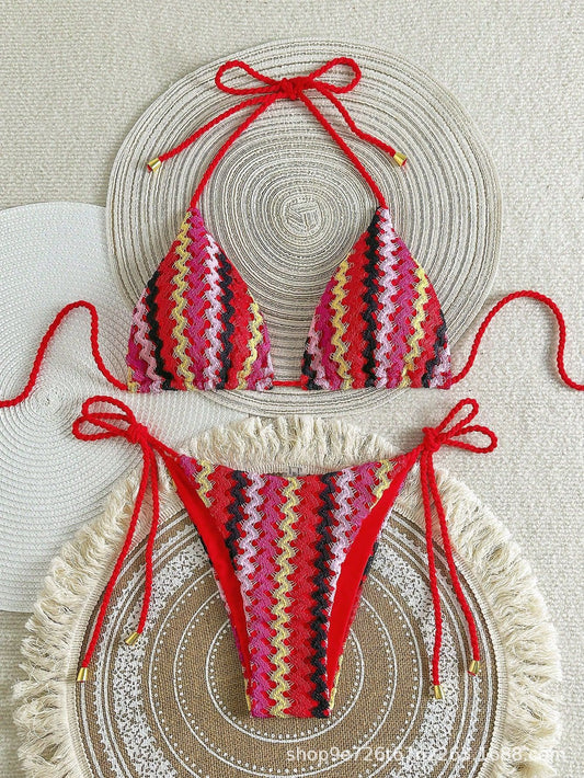 Crocheted bikini set with red and pink pattern on a textured surface


