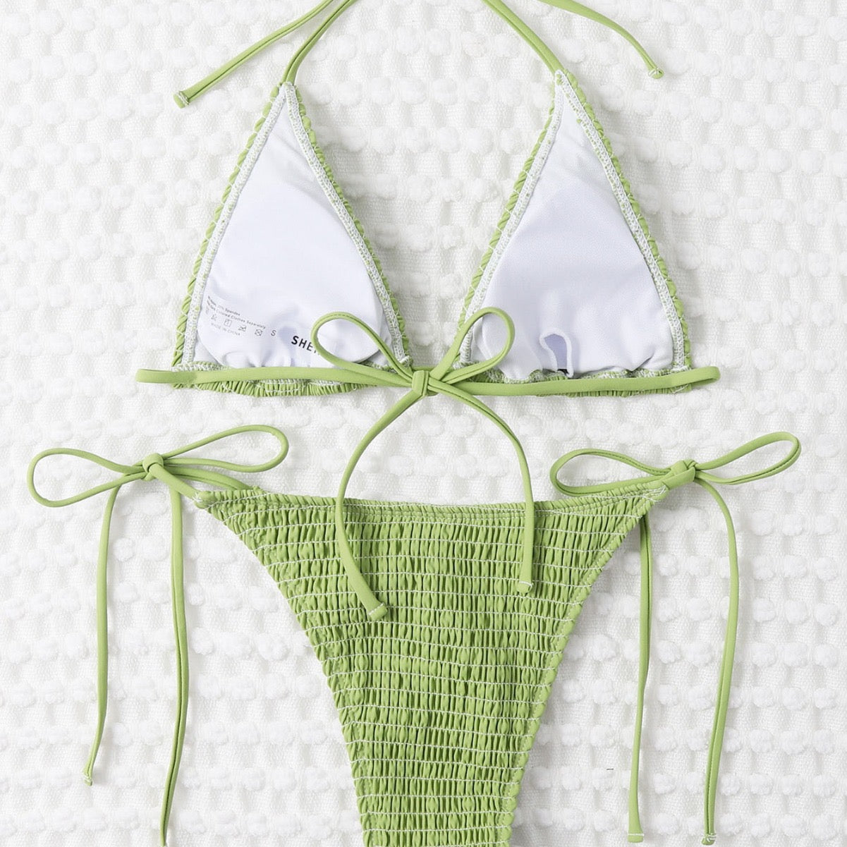 Green and white bikini set on a textured white background

