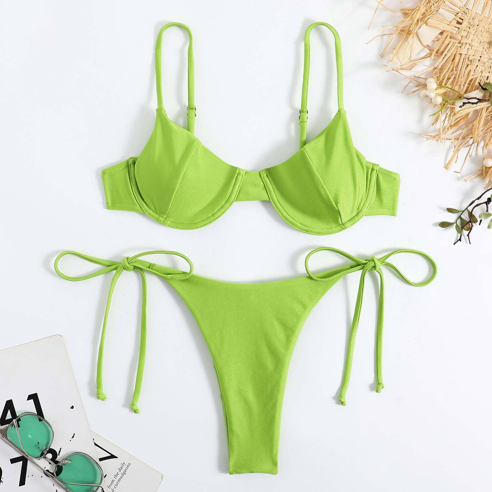  Green bikini set on a white background with a magazine and sunglasses.

