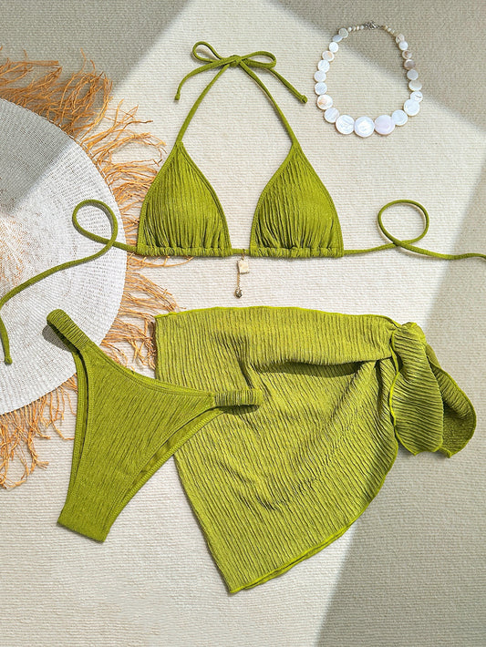 Green bikini set with matching necklace on a textured surface

