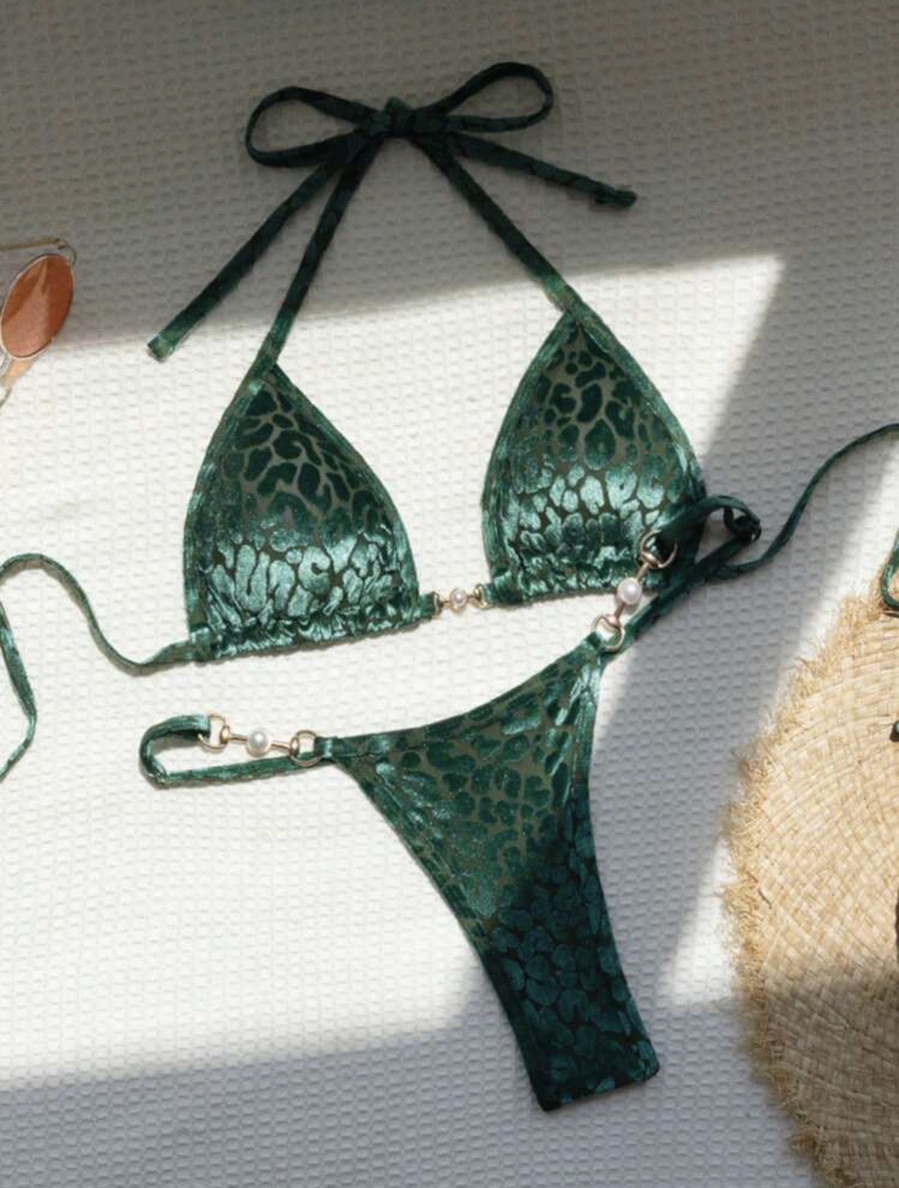 Green lace bikini set on a light surface with a textured object in the background

