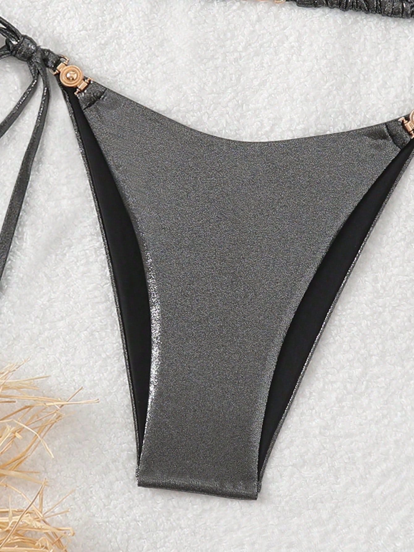 Gray bikini bottom on a textured surface with hay.
