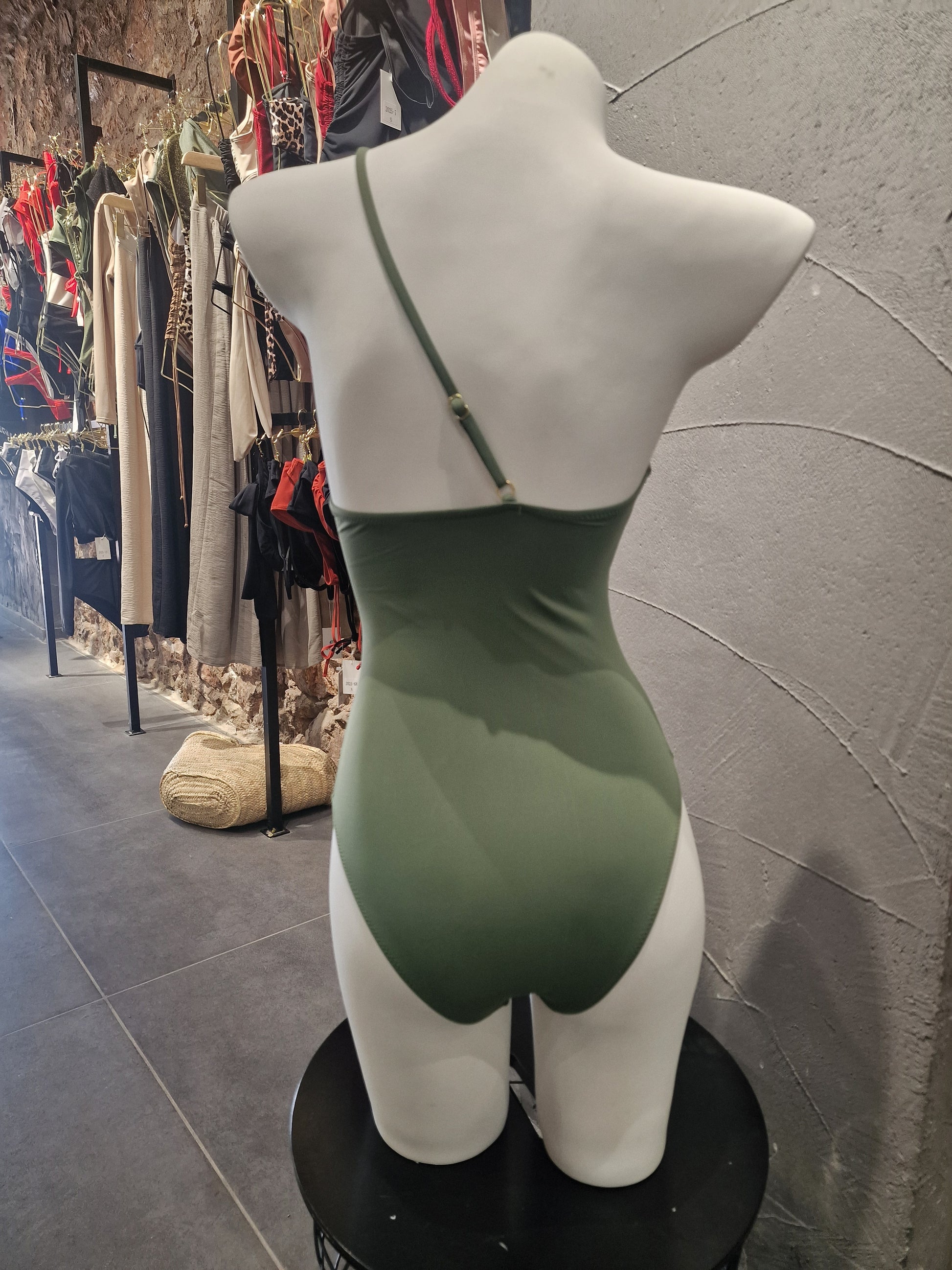 Mannequin wearing a green dress on a tiled floor


