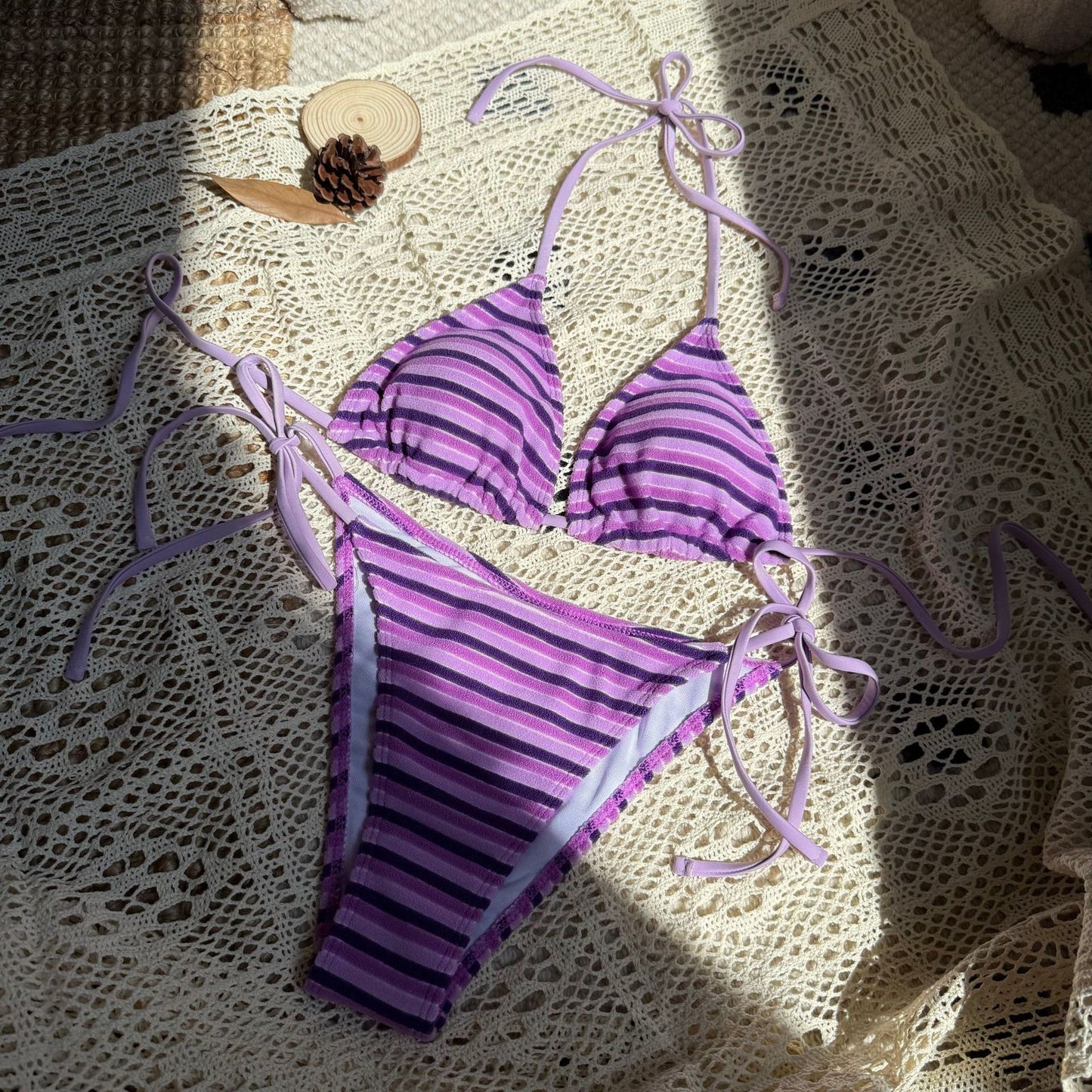 Purple striped bikini set on a textured surface

