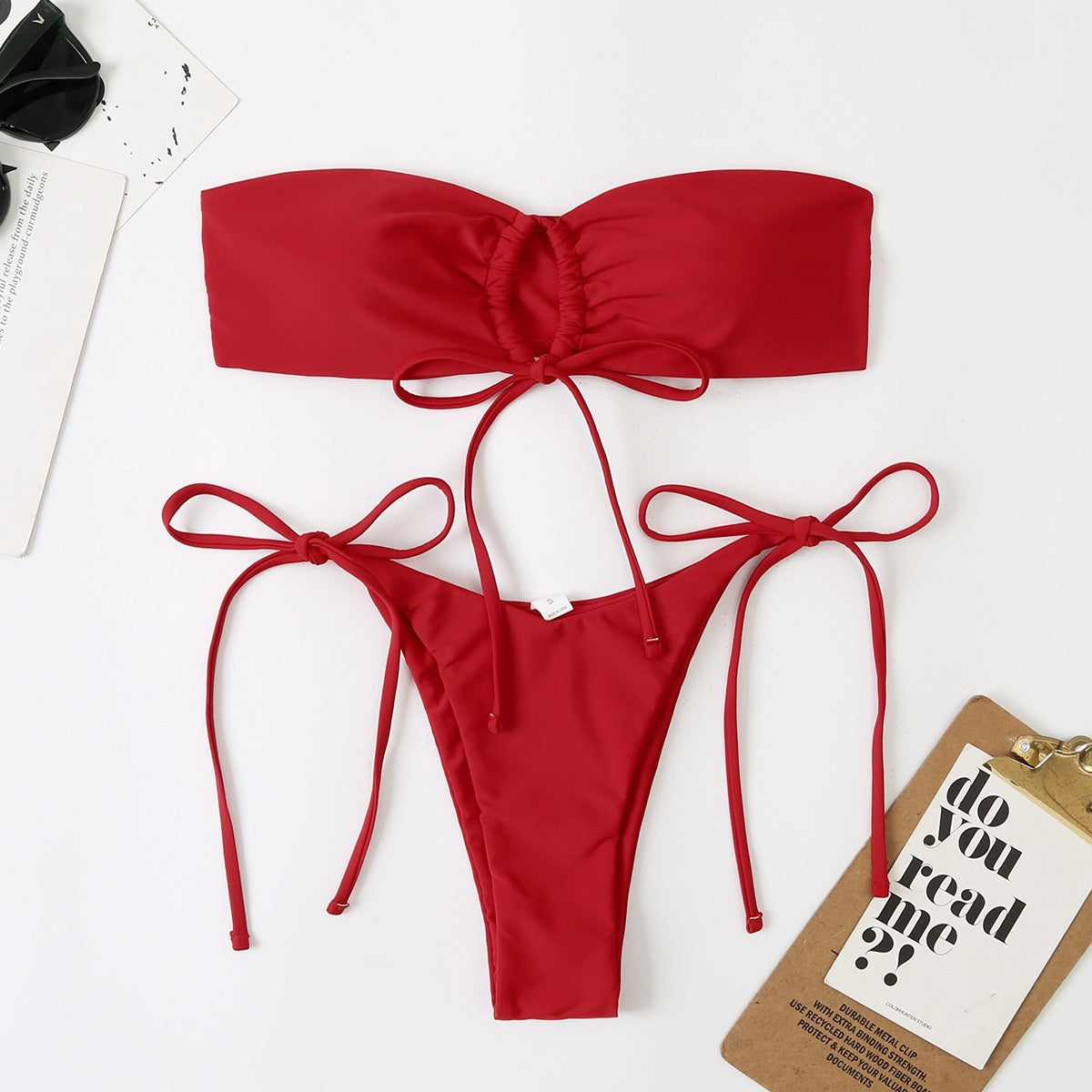 Red bikini set on a white background with a small sign.

