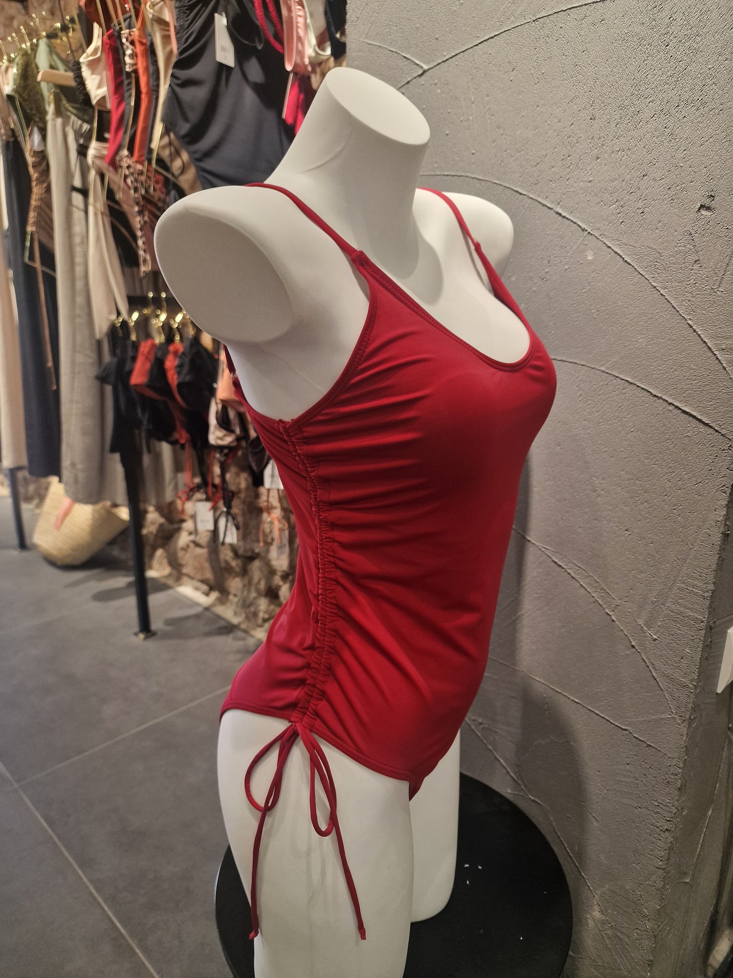 Red dress on a mannequin against a textured wall.

