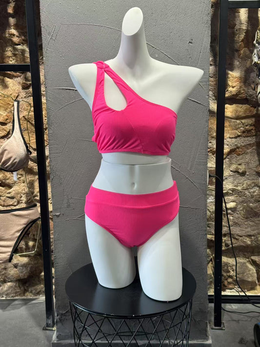 Mannequin wearing a bright pink bikini set against a stone wall.

