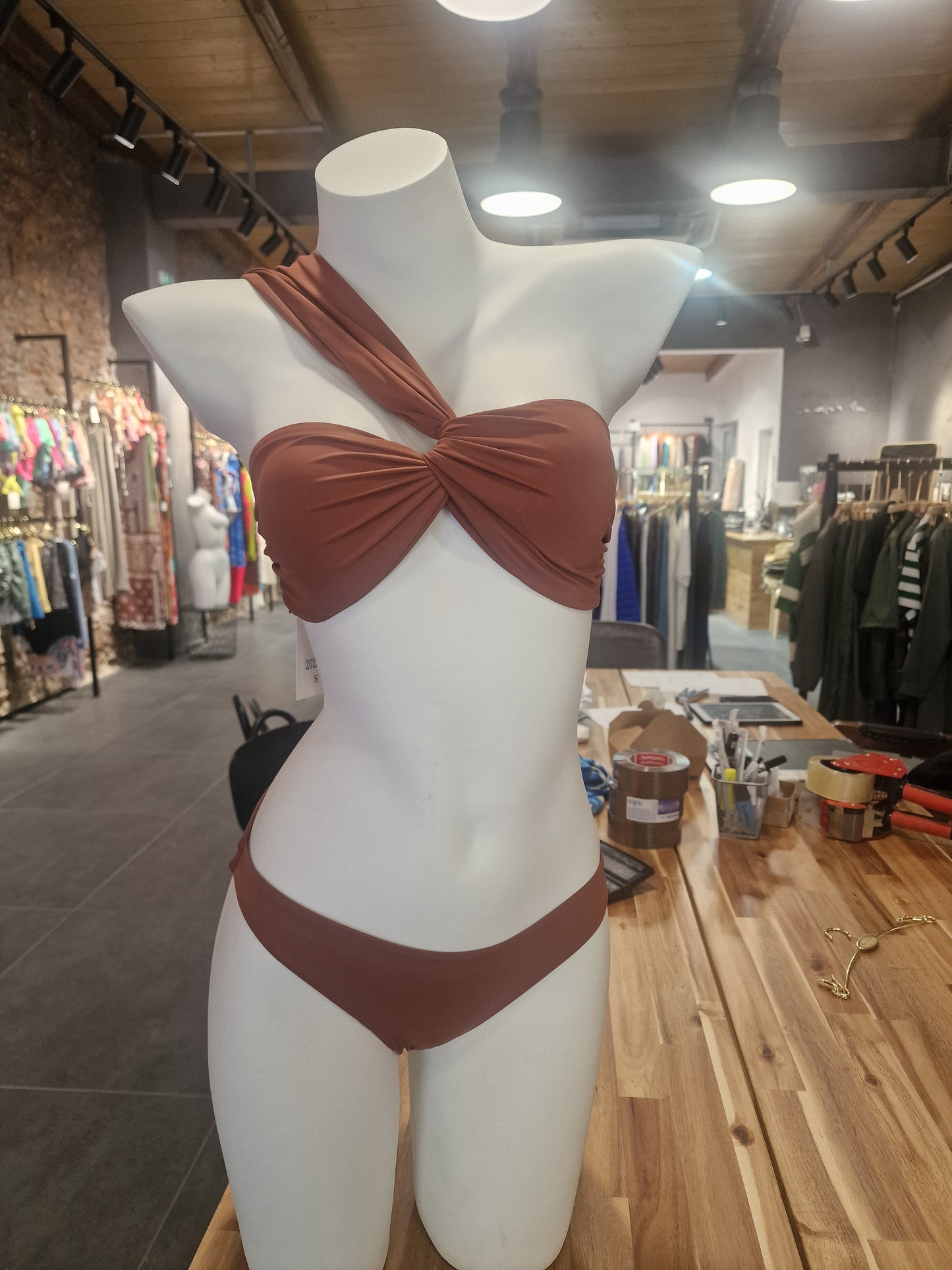 Mannequin wearing a brown bikini in a store setting

